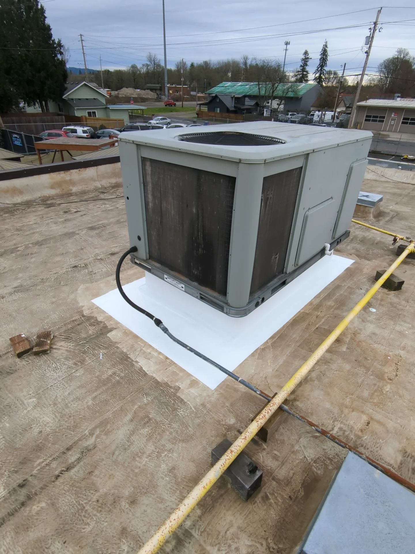 Sealed silicone coating around a rooftop AC unit's curb.