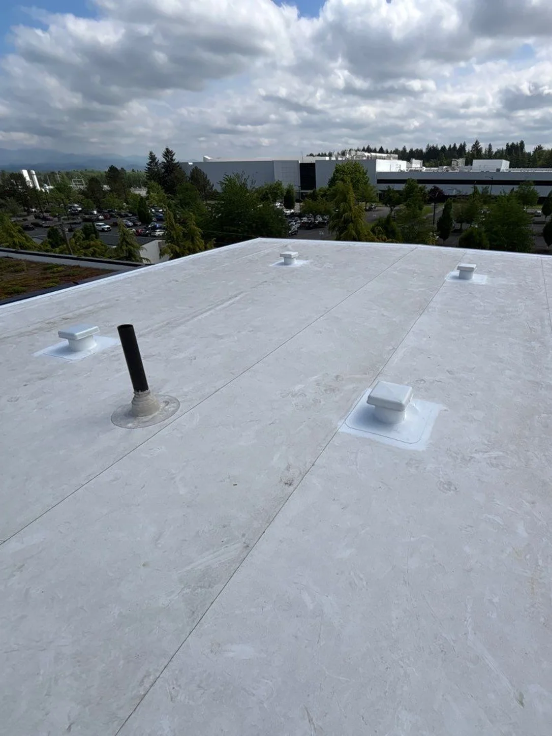 Box vents and a pipe vent set into the white roof membrane.