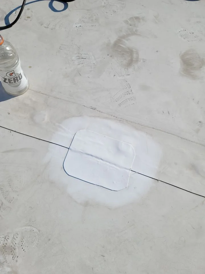 A sealed white patch over a seam on a flat roof.