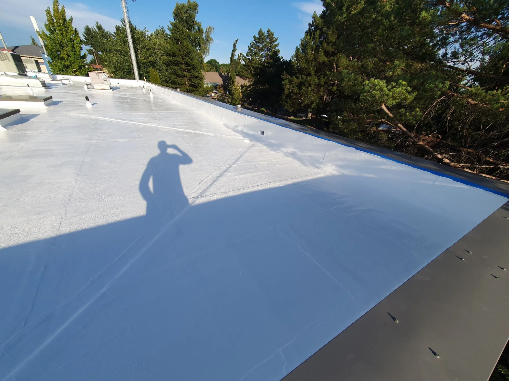 A finished RoofSeal surface beside a clean metal edge, photographed in warm evening light.