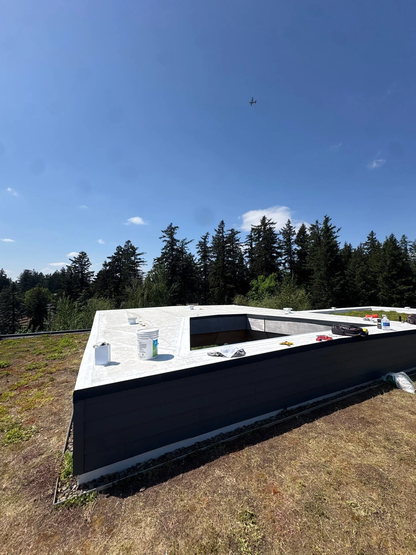 A finished white flat roof on a modern home under clear blue sky.
